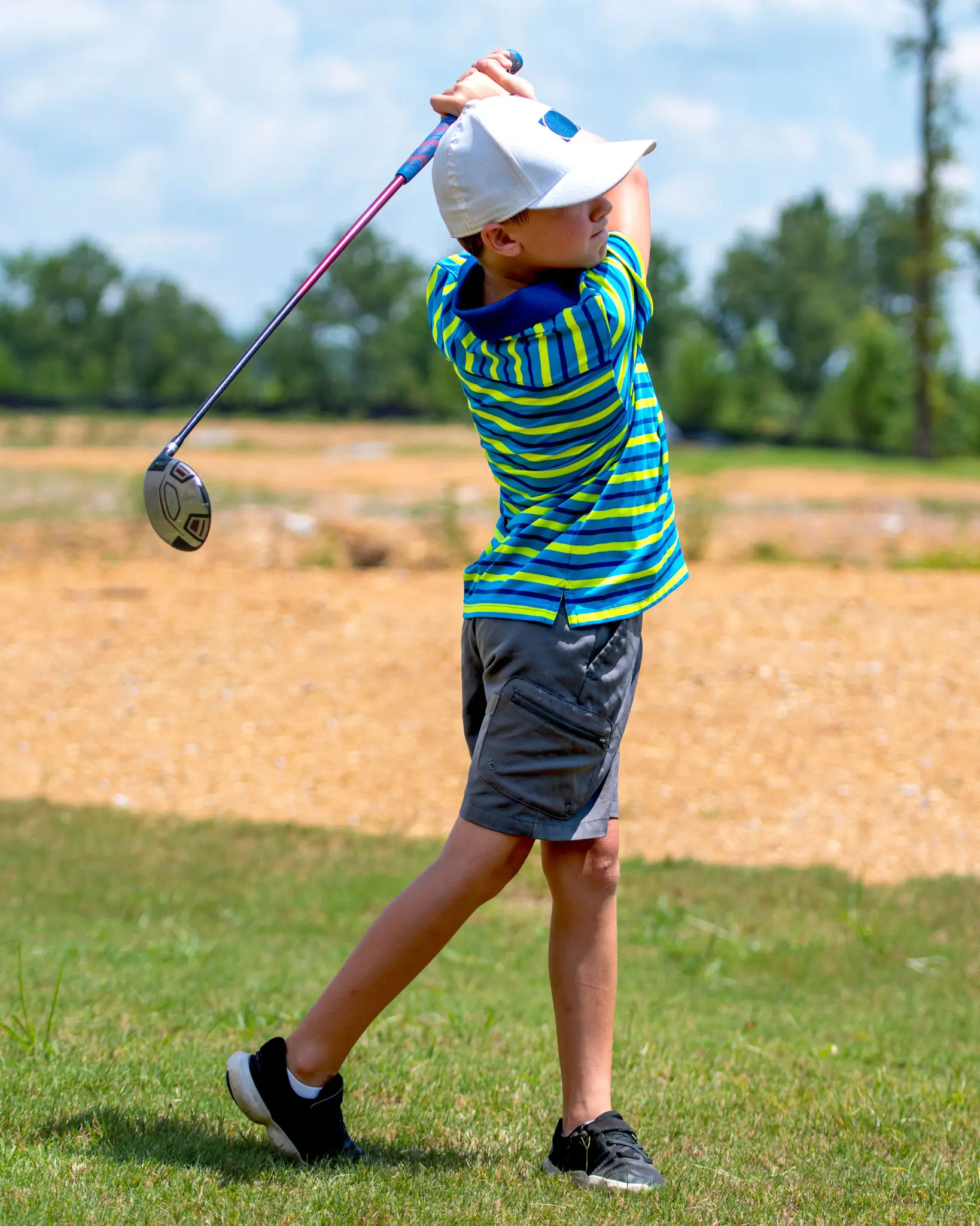 Child playing golf on grassy field.