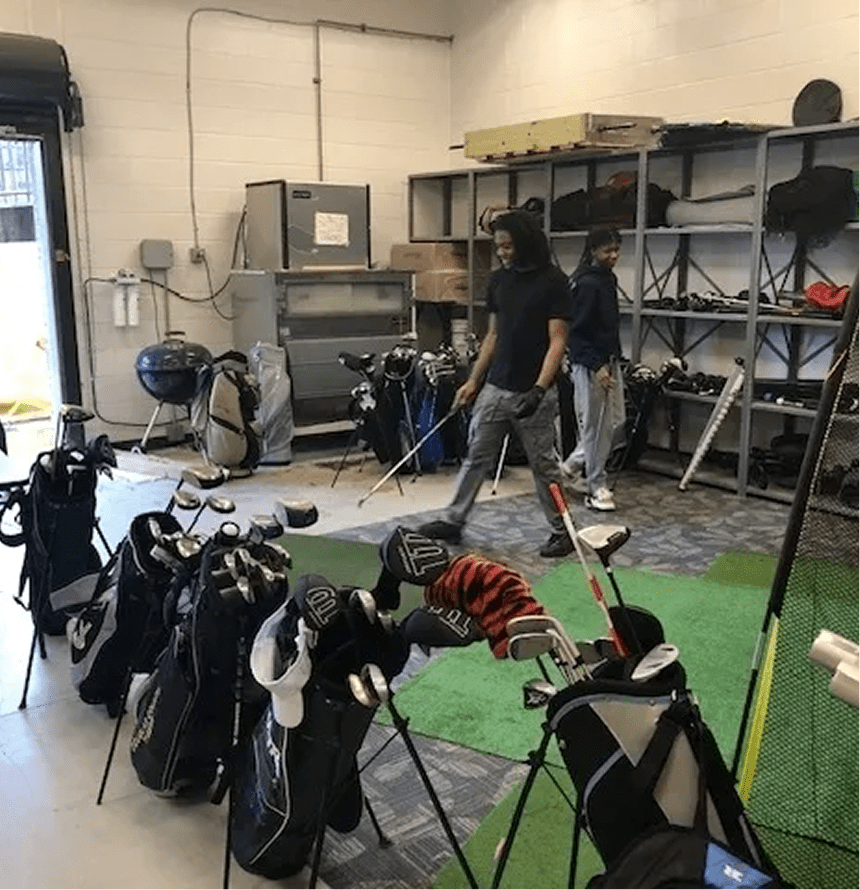 Golf equipment room with people organizing clubs.