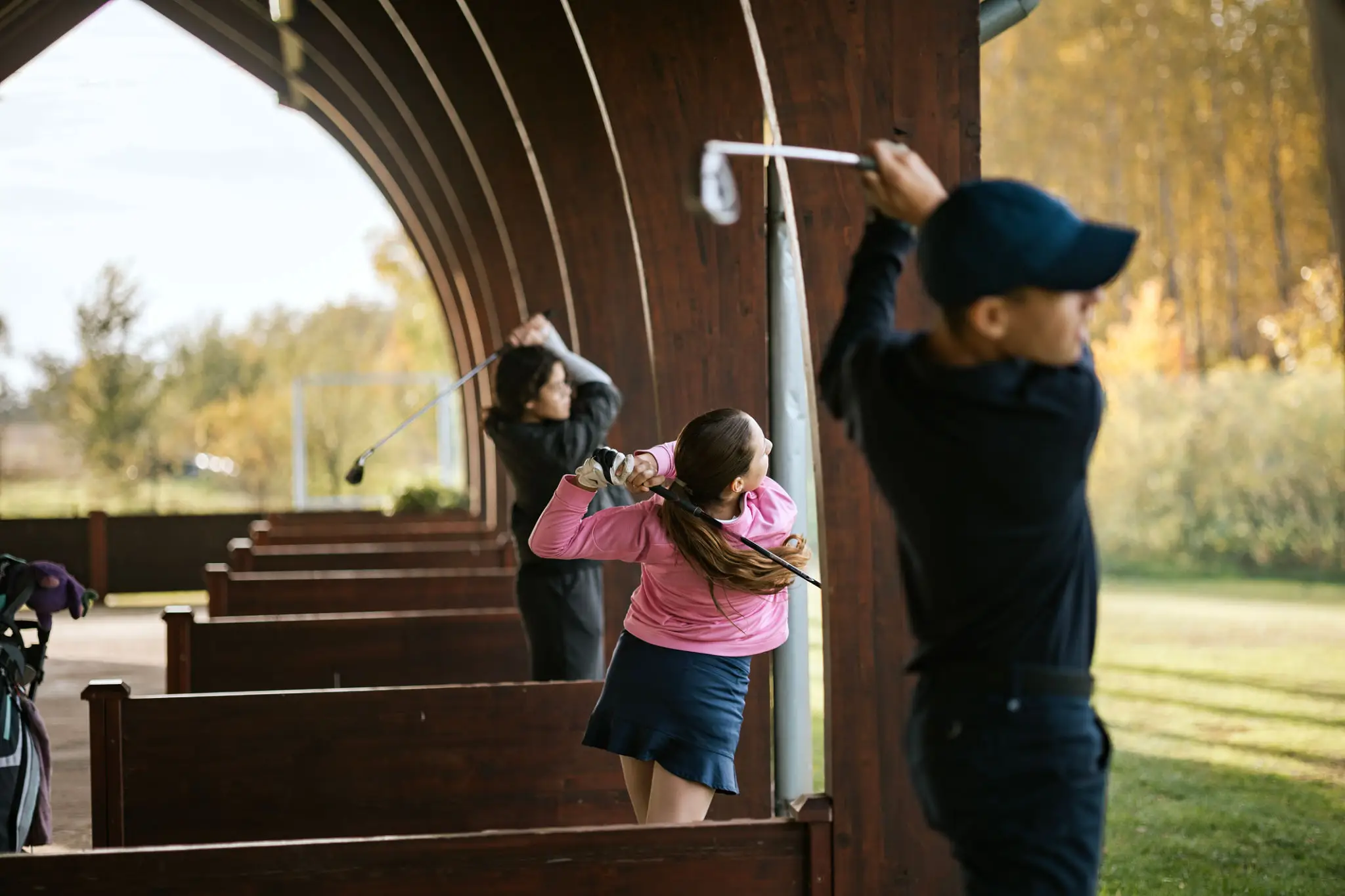 People practicing swings at a golf range.