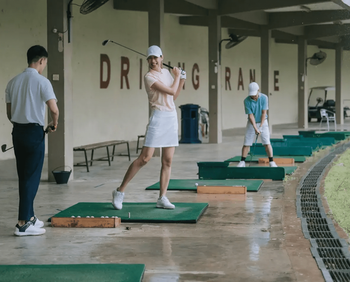 Golfers practicing at an indoor driving range.